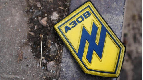 Auf einer Straße in Mariupol liegt ein Abzeichen mit dem Logo des "Asow"-Bataillons. (Quelle: Mihail Andronik/imago images)